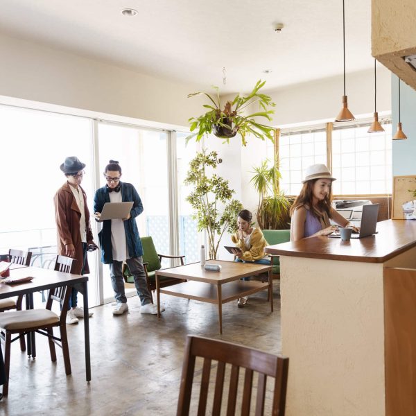 Group of young Japanese professionals working on laptop computers in a co-working space.