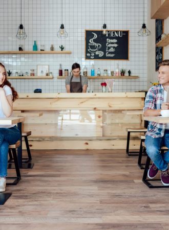 happy young man and woman smiling each other while getting to know in cafe