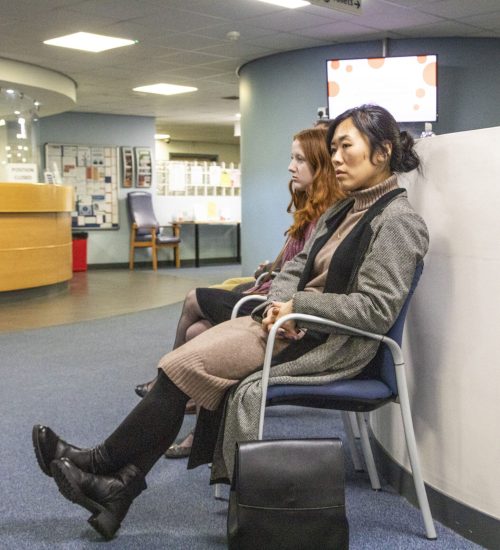 Two people sitting in a waiting area of a medical practice