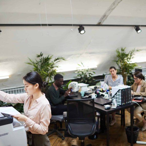 High angle portrait of Asian businesswoman scanning documents while working in office, copy space
